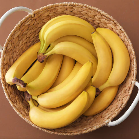 three bunches of Yellow banana in a woven basket on a brown surface