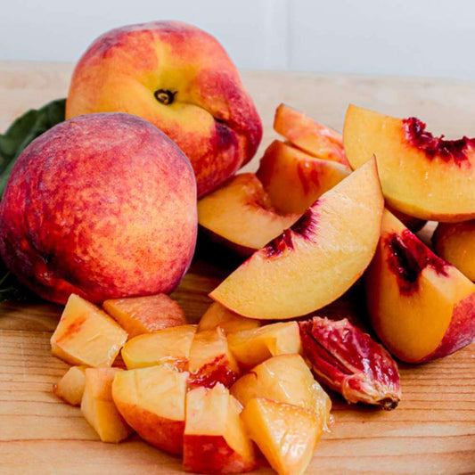 2 peach fruits and diced peaches on a wooden surface 