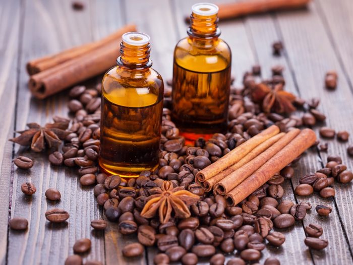 two bottles of coffee essential oil in amber bottles with euro dropper caps and brown coffee beans on a wooden table  