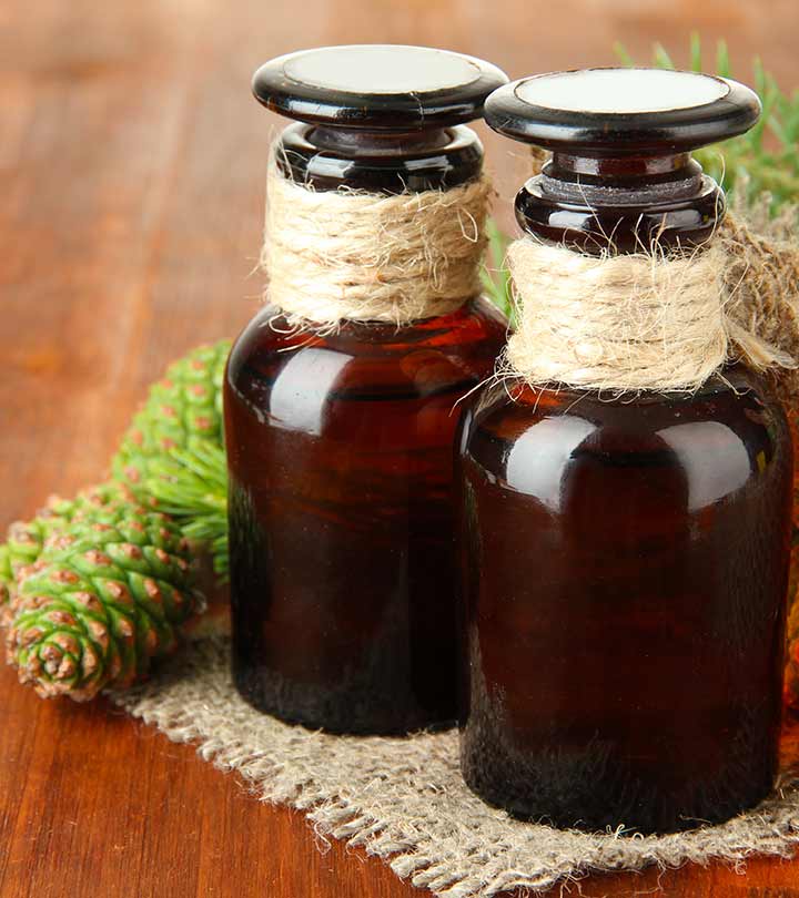 Two amber bottles with flat lids and twine on the bottle neck with castor fruit on a twine fabric all on a wooden surface